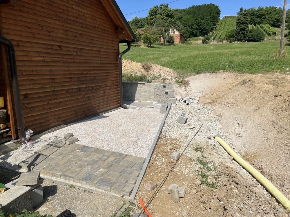 Pripravljena podlaga in tlakovanje dvorišča ob leseni hiši