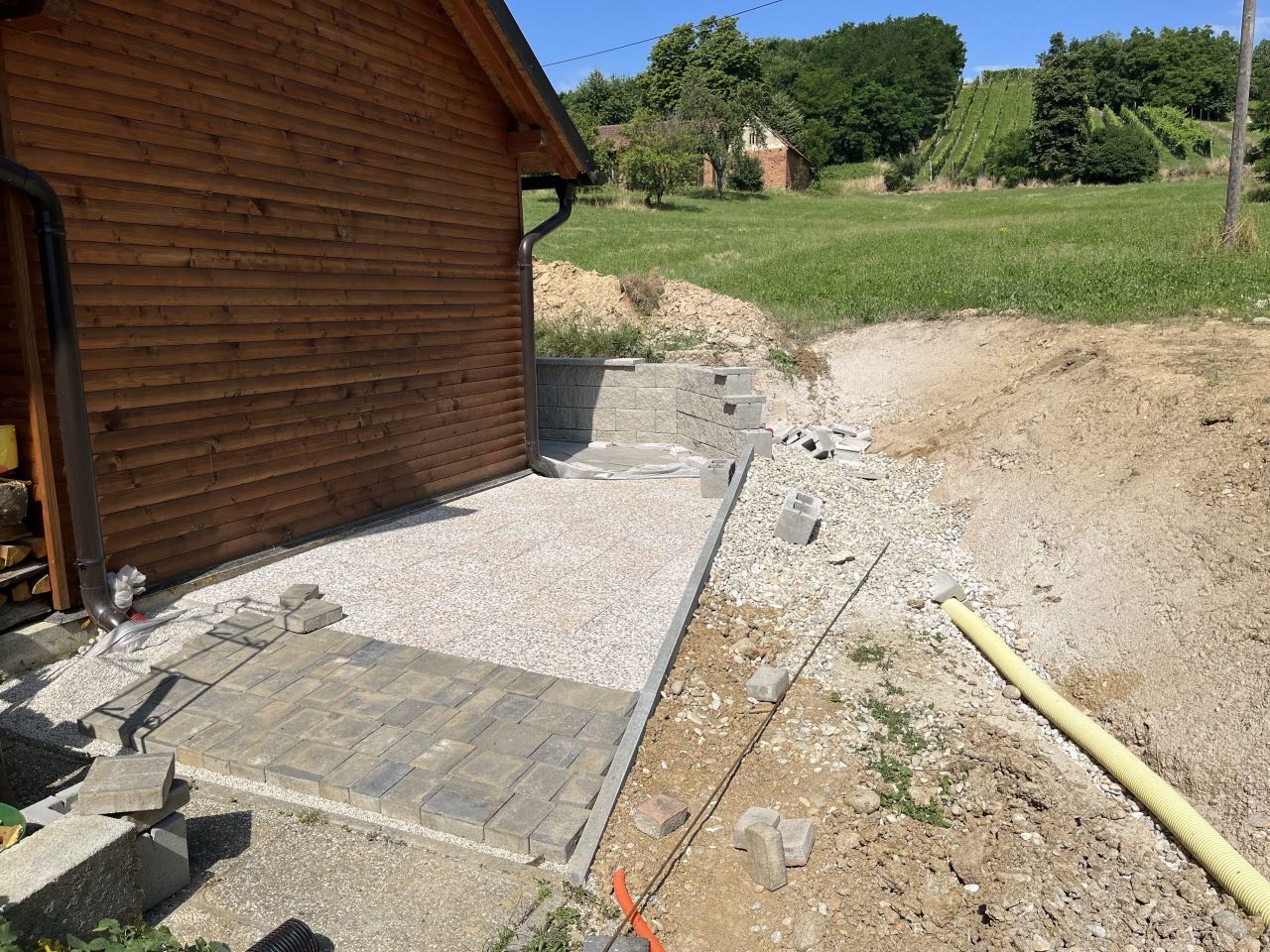 Pripravljena podlaga in tlakovanje dvorišča ob leseni hiši
